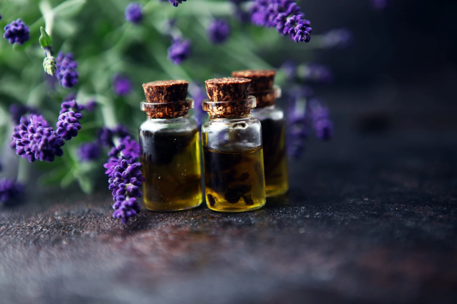 lavender oil in a glass bottle on a background of fresh flowers on table